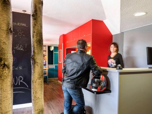 un homme debout devant un comptoir devant une femme dans l'établissement hotelF1 Lyon Saint Priest, à Saint-Priest