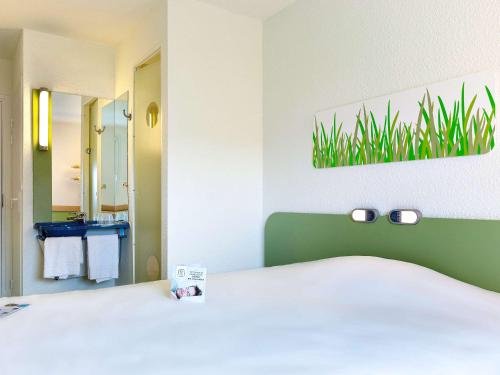 a hotel room with a bed and a bathroom at ibis budget La Roche Sur Yon Vendespace in Mouilleron-le-Captif