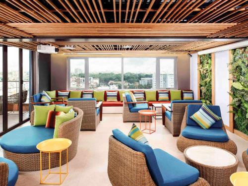 a lobby with chairs and tables and windows at Ibis Saigon Airport in Ho Chi Minh City