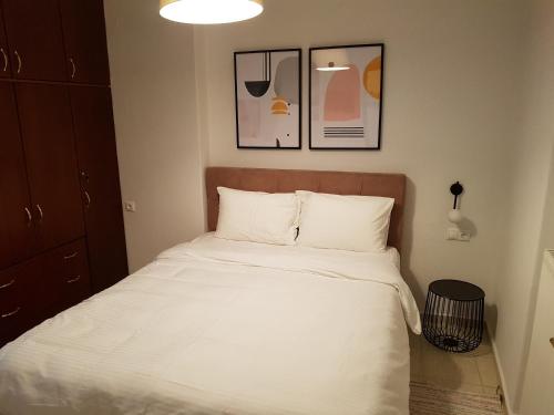 a bed in a bedroom with two pictures on the wall at Stylish Central Apartment in Larisa