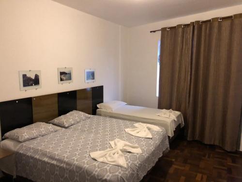 Dos camas en una habitación de hotel con toallas. en AP na Rua das Flores, en Curitiba