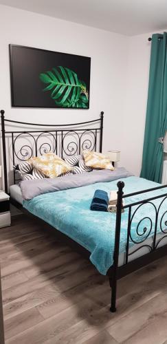 łóżko z czarną ramą z niebieskim kocem i poduszkami w obiekcie Apartament RODZINNY Wałowa Wejherowo w Wejherowie