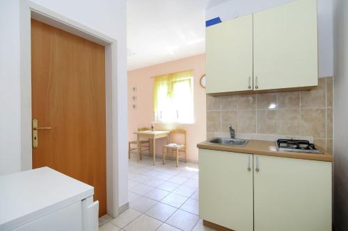 a kitchen with white cabinets and a kitchen with a table at Apartments Tea - parking and grill, 100 m from sea in Rogoznica