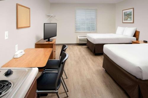 a hotel room with two beds and a desk with a computer at Woodspring Suites Huntsville/ Madison in Madison