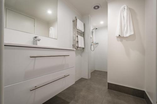 a white bathroom with a shower and a sink at Argosy Motor Inn in Devonport