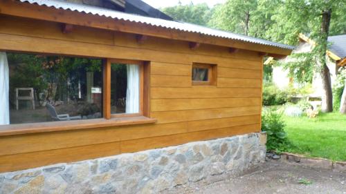 Cabaña de madera con ventana y pared de piedra en Los notros 190 en San Martín de los Andes