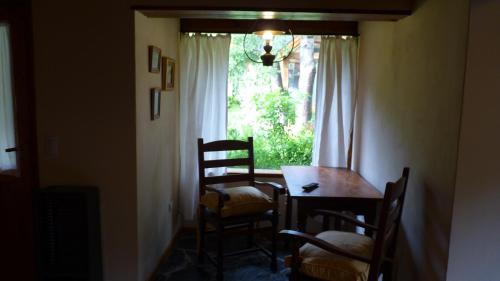 comedor con mesa, sillas y ventana en Los notros 190 en San Martín de los Andes