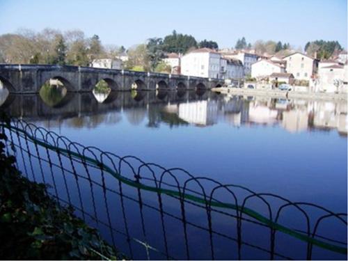 a bridge over a body of water with houses at Maison du Magnolia in Confolens
