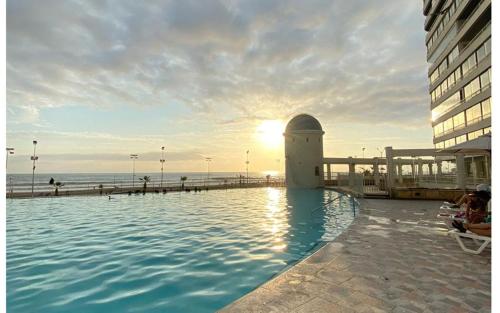 a swimming pool next to a building and the ocean at Condominio Mar Egeo Iquique in Iquique