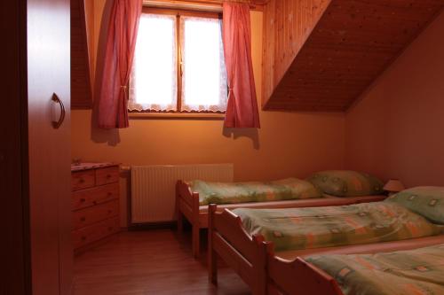 a bedroom with three beds and a window at Rekreačný dom pod Dedovou in Oščadnica