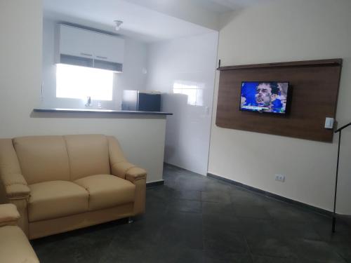uma sala de estar com um sofá e uma televisão de ecrã plano em Sobrado in Village no Guarujá
