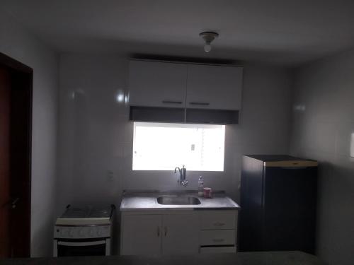uma pequena cozinha com um lavatório e uma janela em Sobrado in Village no Guarujá