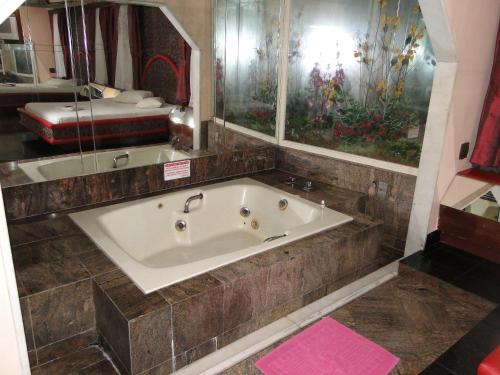 a bath tub in a bathroom with a large mirror at New Star in Rio de Janeiro