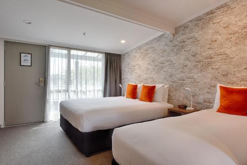 a hotel room with two beds and a brick wall at Croydon Lodge in Gore