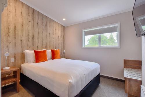 a bedroom with a bed with orange pillows and a window at Croydon Lodge in Gore