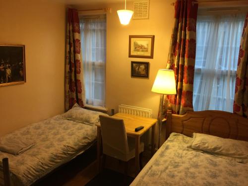 a bedroom with two beds and a table with a lamp at Central Greenwich guest rooms in London