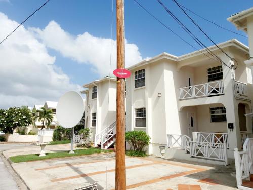 a white house with a red sign on a pole at Clearwater Apartments in Christ Church