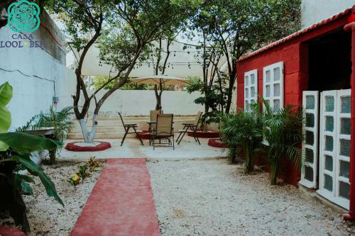un patio avec des tables et des chaises et un bâtiment rouge dans l'établissement Casa Lool Beh, à Mérida