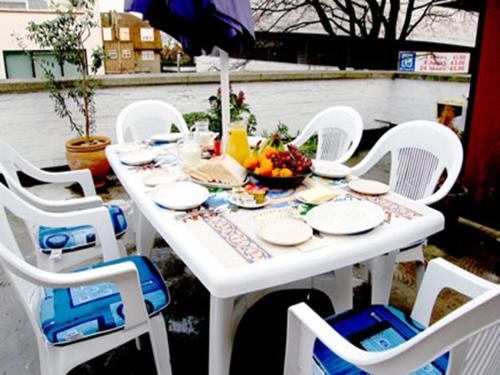a white table with white chairs and a bowl of fruit at St. George's Lodge in Kingston upon Thames