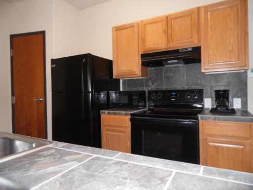 a kitchen with black appliances and wooden cabinets at Hotel Cotulla in Cotulla