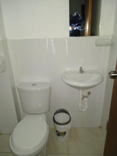 a white bathroom with a toilet and a sink at BACHÍG Hospedaje in Moyobamba