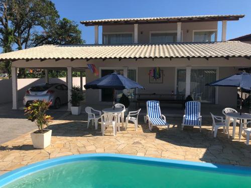 una casa con sillas y sombrillas y una piscina en Mundo Livre Guest House, en Penha