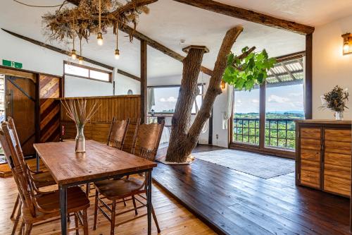 uma sala de jantar com uma mesa e cadeiras e uma árvore em Tree-house Hotel Morinosubako em Nakijin