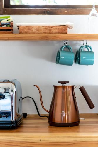 a tea kettle sitting on a counter next to a toaster at Tree-house Hotel Morinosubako in Nakijin