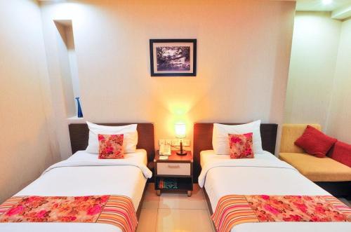 a hotel room with two beds and a couch at Daima Hotel Padang in Padang