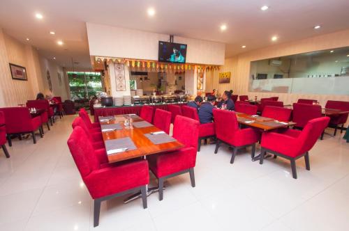 une salle à manger avec des chaises et des tables rouges dans un restaurant dans l'établissement Daima Hotel Padang, à Padang