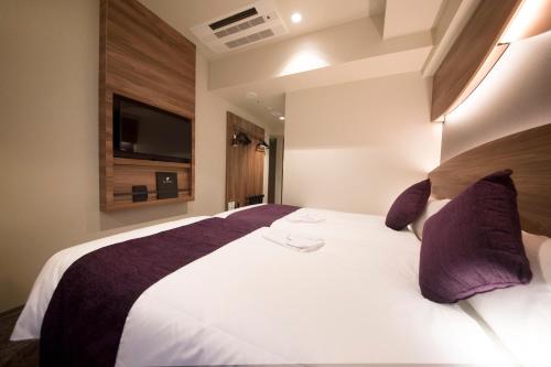 a bedroom with a large white bed with purple pillows at Quintessa Hotel Tokyo Ginza in Tokyo
