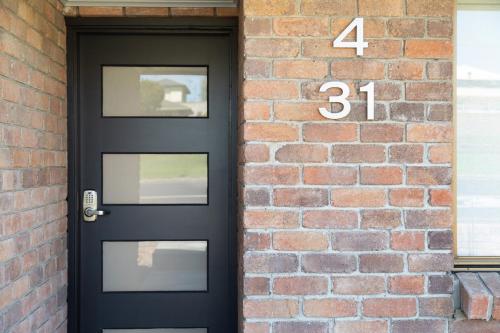 a black door with the number on a brick wall at City Four Apartment in Mount Gambier