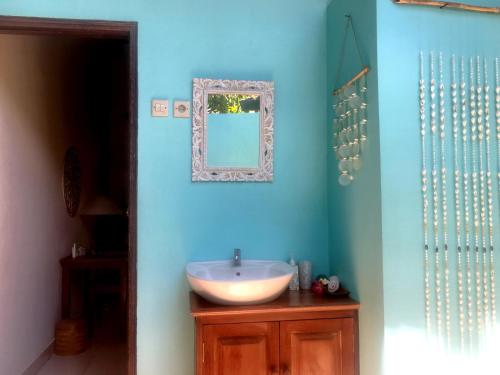 a blue bathroom with a sink and a mirror at Mango Moon in Pemuteran