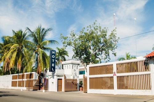 a white building with a gate and palm trees at Hotel Maioris Navolato in San Pedro
