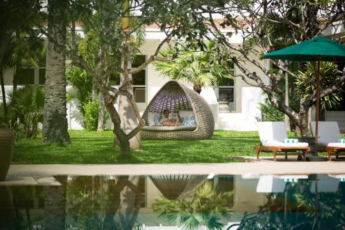 a pool of water with a hammock in a yard at Raffles Grand Hotel d'Angkor in Siem Reap