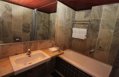 a bathroom with a sink and a tub and a shower at Hotel Merihovi in Kemi