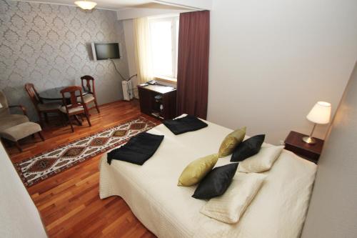 a bedroom with a white bed with black pillows at Hotel Merihovi in Kemi