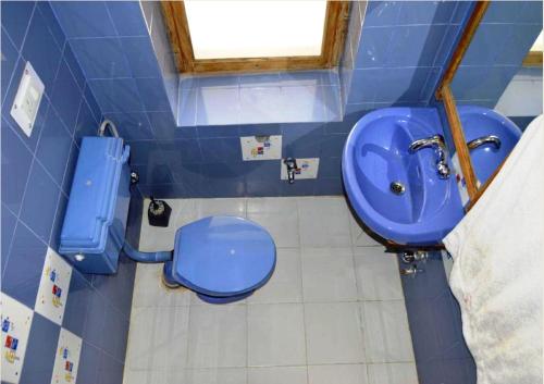 Baño azul con aseo y lavamanos en Hotel Mahay Palace en Leh