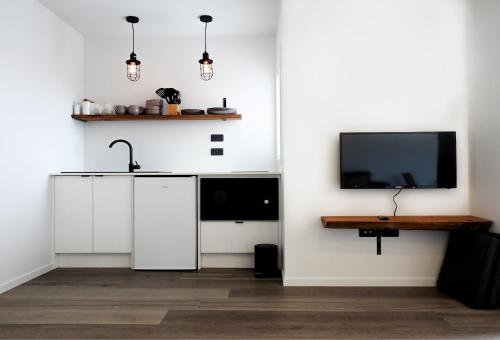 uma cozinha com armários brancos e uma televisão de ecrã plano em The Loft Apartments em Westport