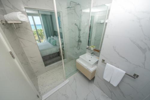 a white bathroom with a sink and a shower at Ocean V Hotel in Pereybere