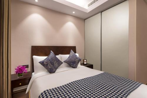 a bedroom with a large white bed with blue pillows at Somerset Emerald City Suzhou in Suzhou