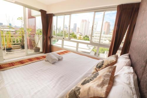 a bed in a room with a large window at Baan Sabai Rama IV Apartment in Bangkok