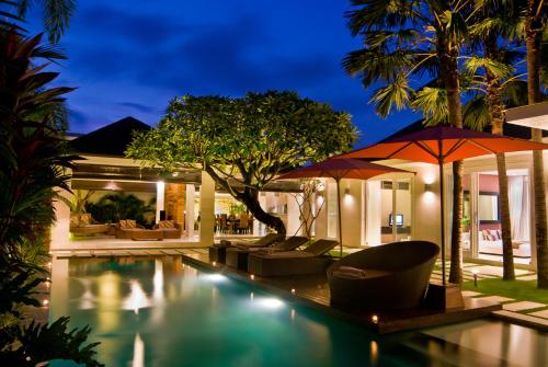 a villa with a swimming pool at night at Chandra Bali Villas in Seminyak