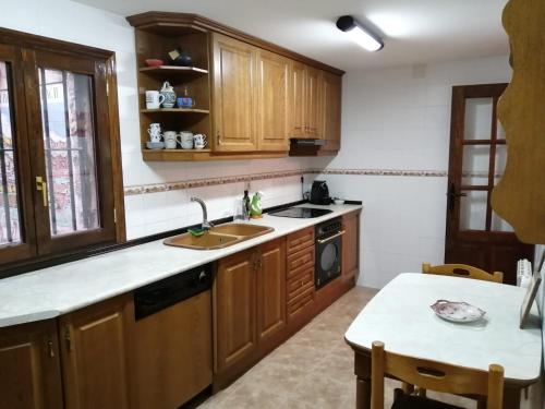 cocina con armarios de madera, fregadero y mesa en CASA CENTRO ALBARRACIN en Albarracín