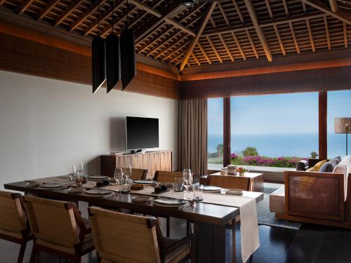 a dining room with a table with chairs and a television at Six Senses Uluwatu in Uluwatu