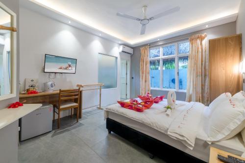 1 dormitorio con escritorio y 1 cama con almohadas blancas en Koimala Beach Ukulhas, en Ukulhas