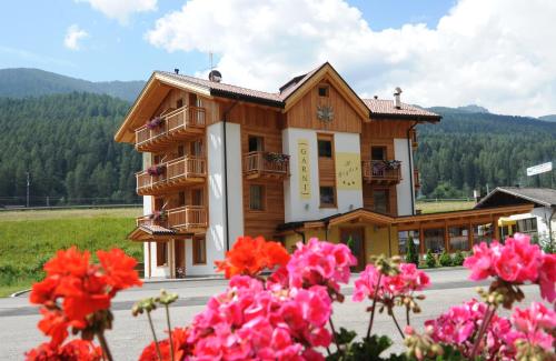 un bâtiment avec des fleurs roses devant lui dans l'établissement Residence Garnì Il Giglio, à Commezzadura