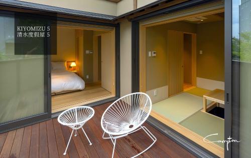 a balcony with two chairs and a bed in a room at Campton Kiyomizu Vacation Rental in Kyoto