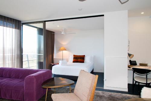 une chambre d'hôtel avec un lit et un canapé violet dans l'établissement Nishi Apartments Eco Living by Ovolo, à Canberra