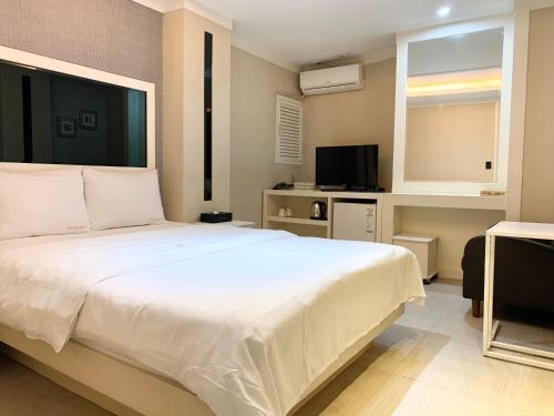 um quarto com uma grande cama branca e uma televisão em Princess Hotel em Seul